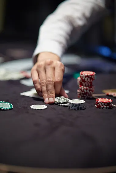 Людина в білому сорочці переміщує покерні фішки на казино-столі. Сцена випромінює фокус і стратегічну напругу, з купами червоних і зелених фішок.